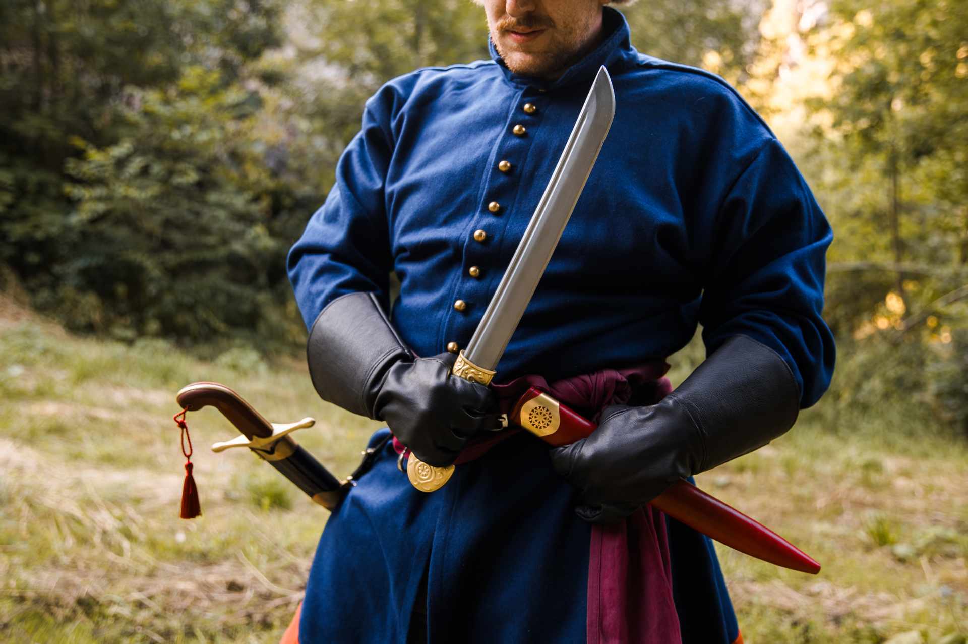 Khanjar dagger held with its curved steel blade drawn and ornate brass hilt