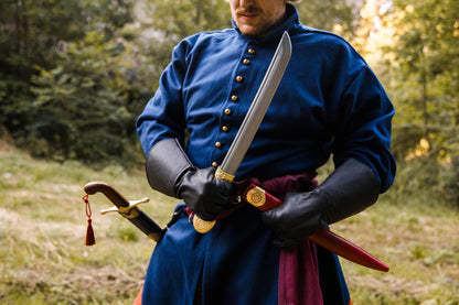 Khanjar dagger held with its curved steel blade drawn and ornate brass hilt