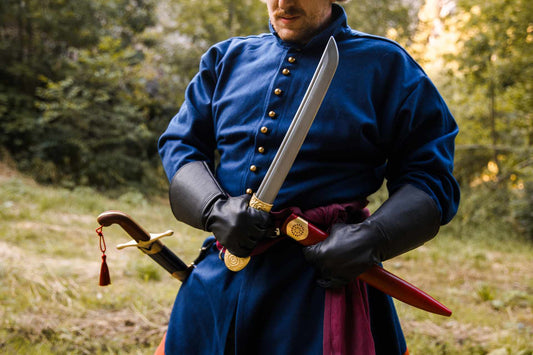Khanjar dagger held with its curved steel blade drawn and ornate brass hilt