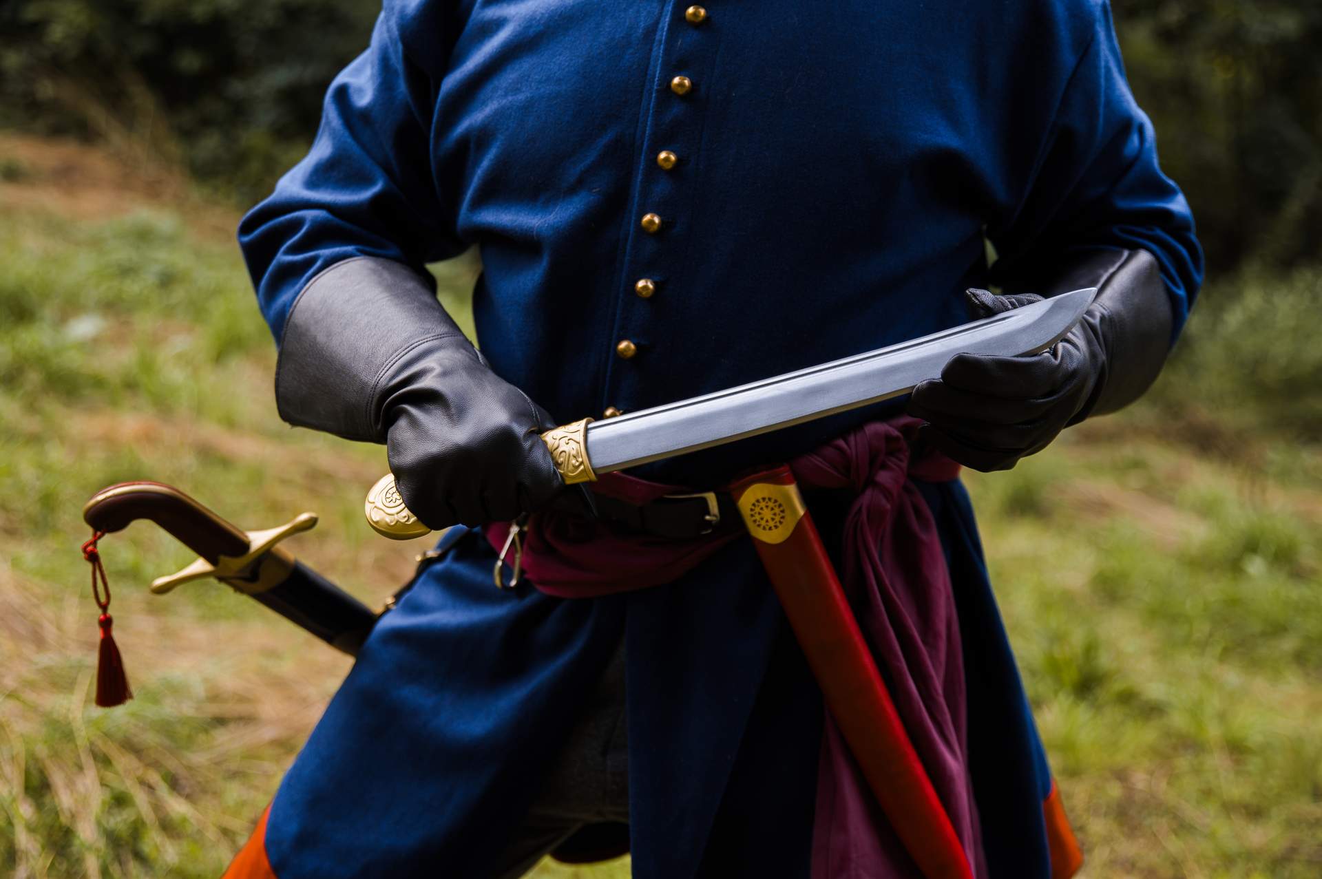 Khanjar dagger with curved steel blade and brass hilt held in both hands