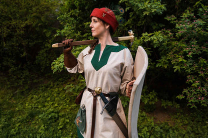 Woman medieval warrior in red round cap with sword and shield medieval costume