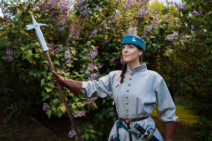 Woman medieval warrior in teal wool round cap with halberd polearm weapon