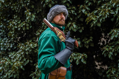 Medieval reenactor in green coat fur hat with wheellock blaster on shoulder outdoor LARP