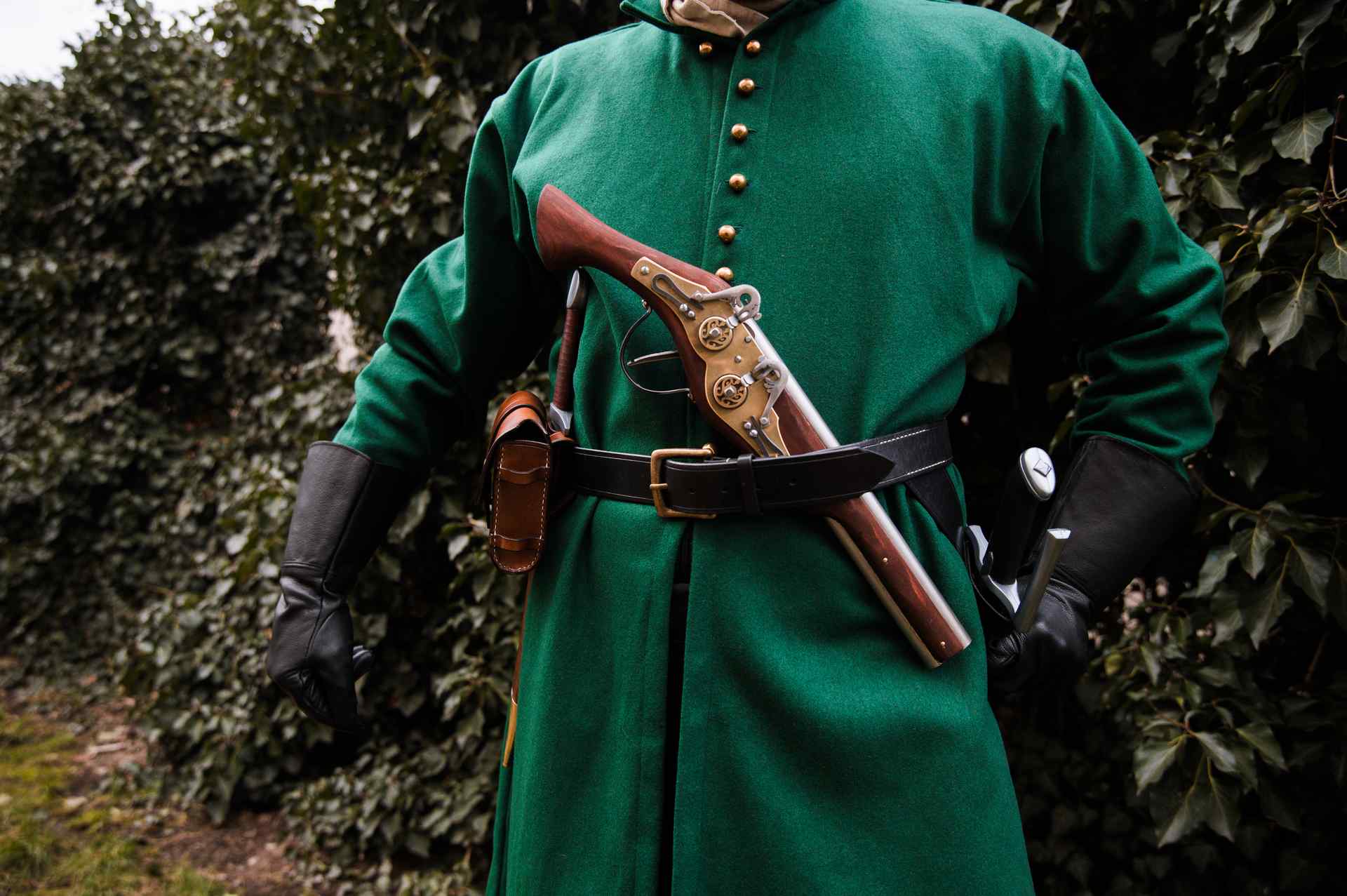 Medieval soldier in green coat with leather belt and holster detail showing wheellock blaster pistol LARP