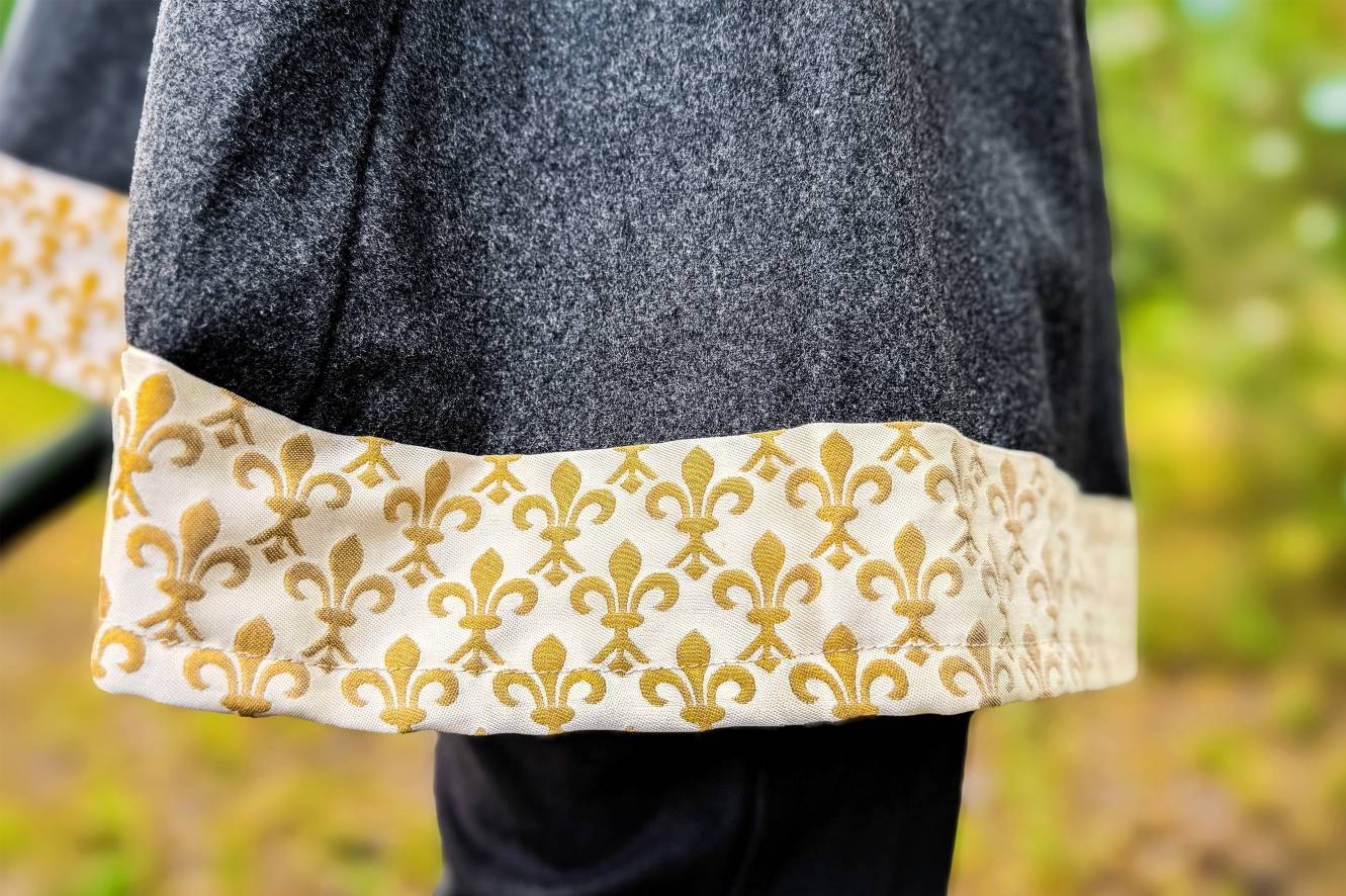 Close-up of coat hem with gold fleur-de-lis trim