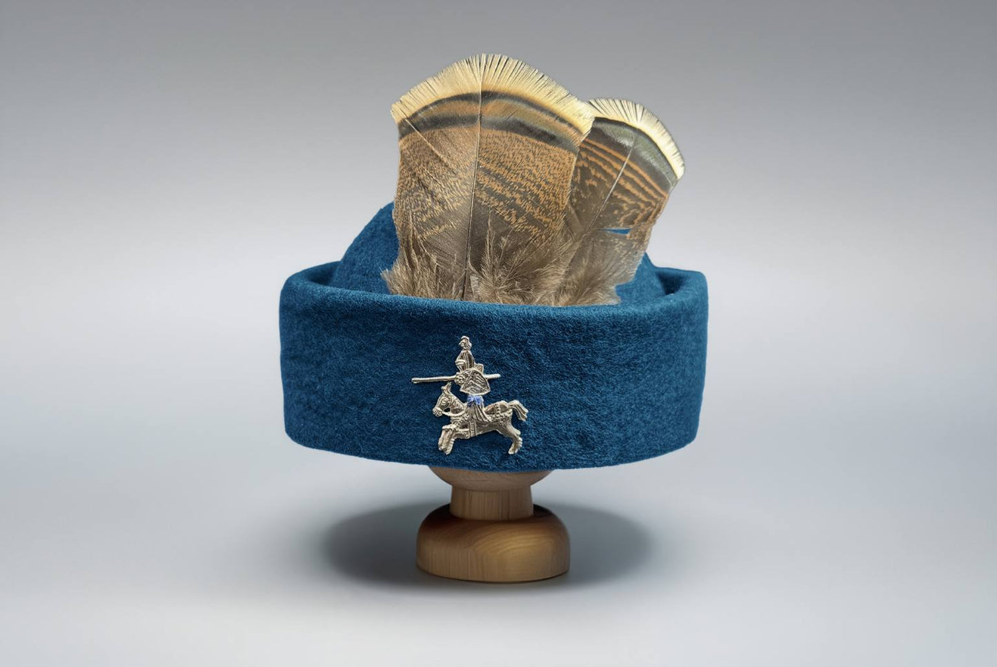 Blue wool round cap with large feathered plume and golden ornament brooch