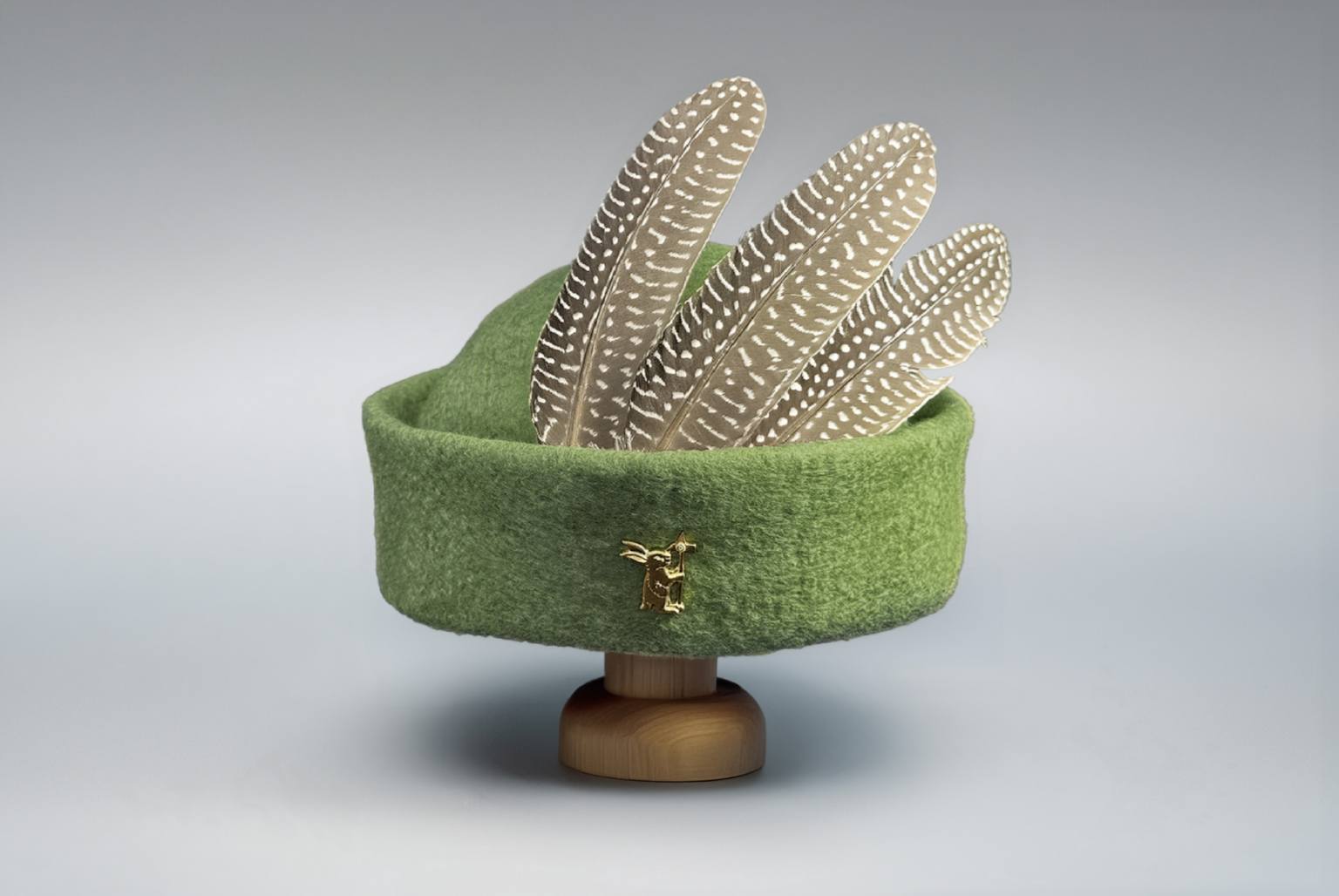 Green round cap wool felt hat with feathers and brass badge on wooden stand display