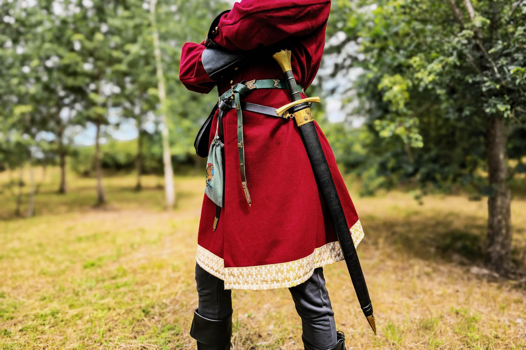 Red medieval coat with gold trim, back view with sword belt